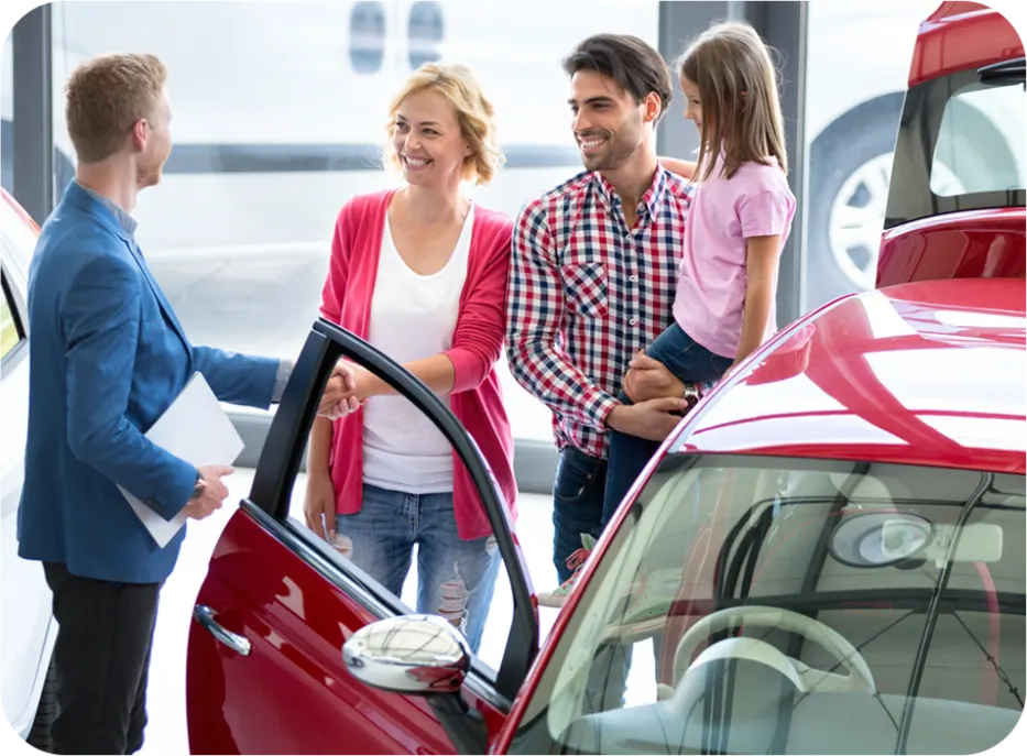 Family at a car dealership being assisted by a salesperson. Automotive reputation management services help increase customer satisfaction and drive sales.