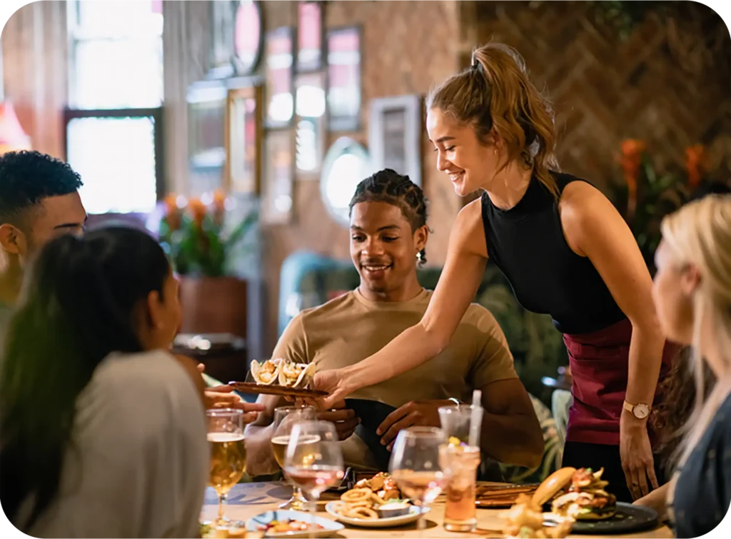 A waitress serving diners at a busy restaurant.